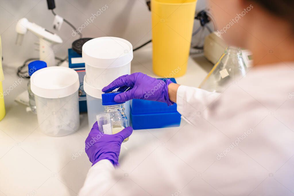 Scientist holding flask in front experiment boxes