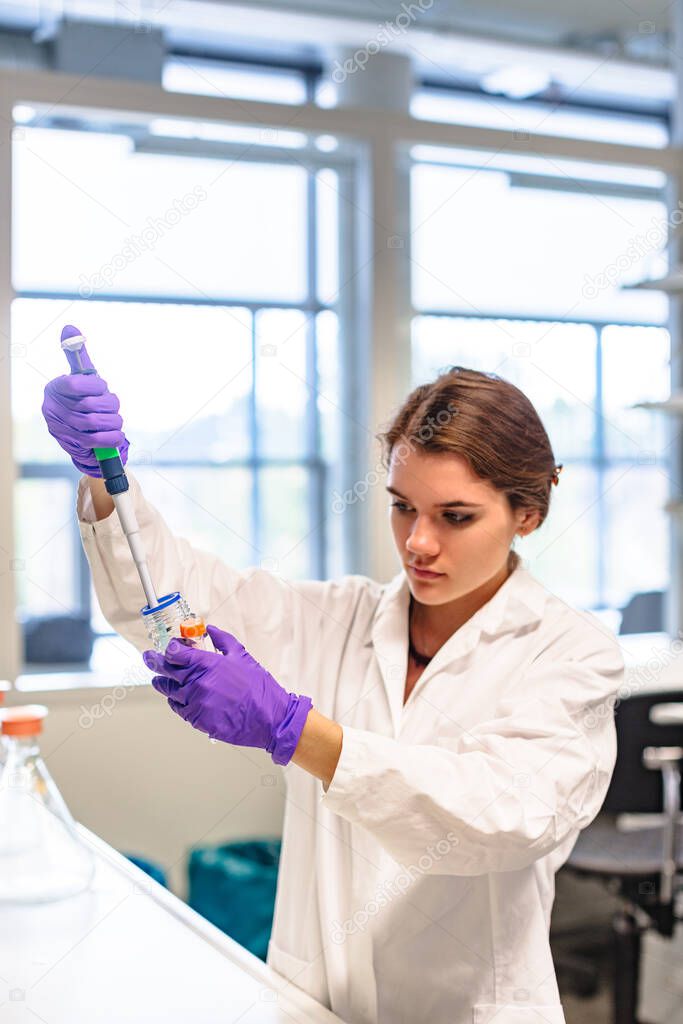 Girl scientist pours liquid in flask with pipette