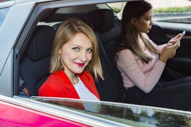 Kız arkadaşıyla arabaya biniyor. Akıllı telefonuyla meşgul.