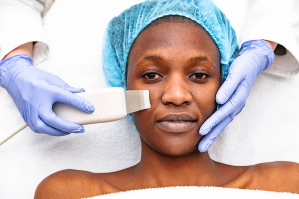 Güzellik uzmanı kadın yüzünde ultrason ameliyatı yapıyor.