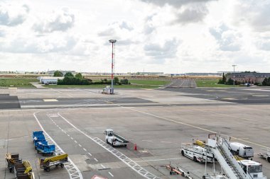 Üzerinde araçlar ve yükleyiciler olan havaalanı pisti.