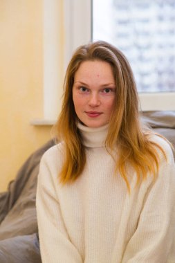 Pencere arkasında süveter giyen genç kız