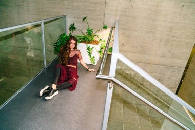 Yeşil bitkilerle birlikte tencerenin yanında oturan bir kız.