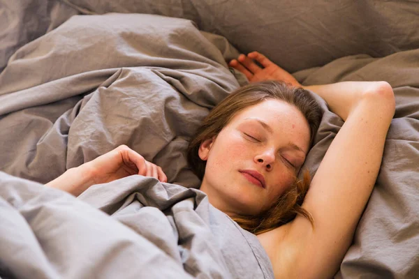 어린 소녀는 회색 린네르의 침실에서 혼자 잠을 잔다 — 스톡 사진