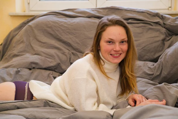 Menina bonita deitada na cama no apartamento moderno — Fotografia de Stock