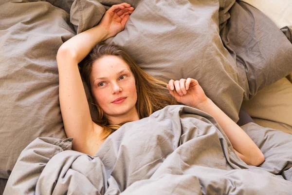 Młoda kobieta rozciągająca się w łóżku budzi się rano — Zdjęcie stockowe
