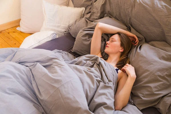 Chica duerme solo bajo cubiertas entre muchas almohadas —  Fotos de Stock