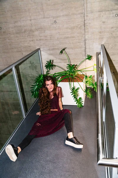 Mulher jovem senta-se com as pernas abertas ao lado da planta — Fotografia de Stock