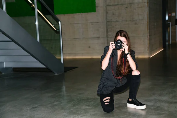 Девушка смотрит в объектив камеры и фотографирует — стоковое фото