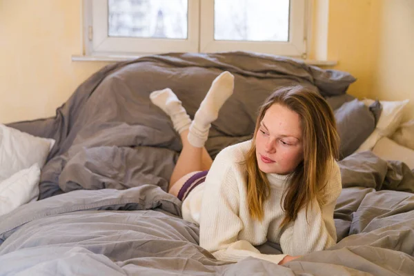 Hermosa chica acostada en la cama en apartamento moderno —  Fotos de Stock