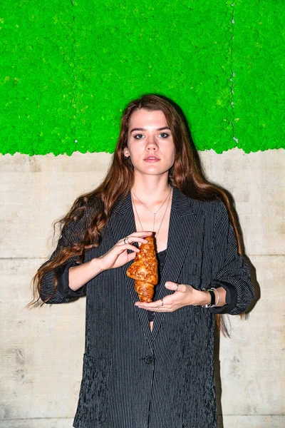 Composição simétrica: menina fica com croissant com fundo verde — Fotografia de Stock