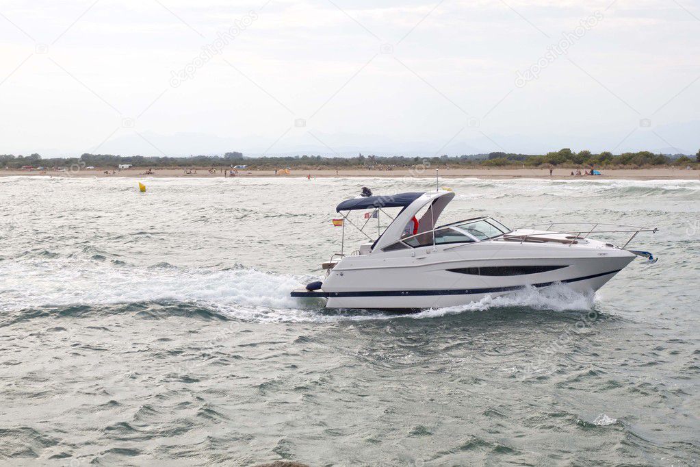 white boat arriving at the spanish coast making waves