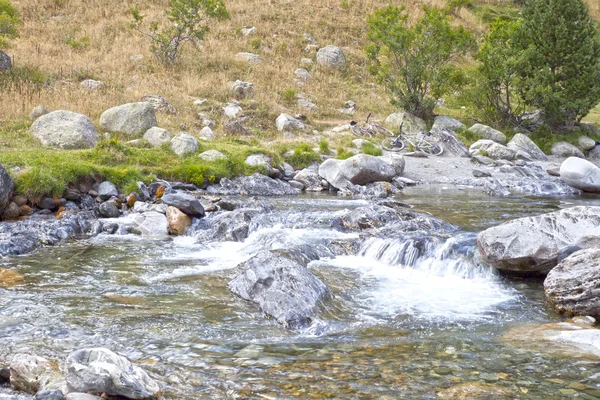 Два велосипеда на берегу реки, полных камней — стоковое фото