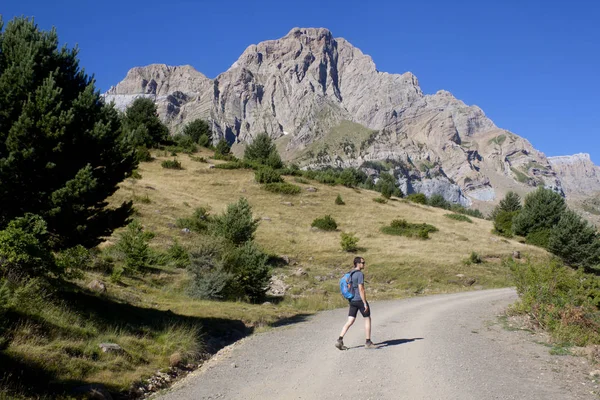 Tipo caminando con una montaña cordillera detrás de él — Foto de Stock