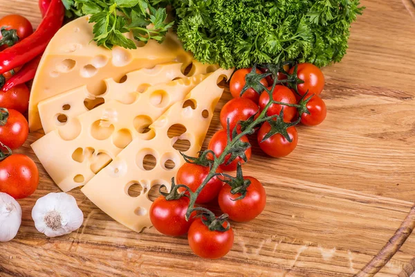 Formaggio con verdure fresche su uno sfondo di legno — Foto Stock