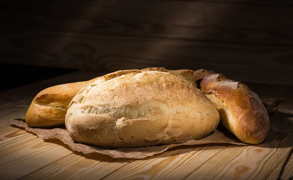 Auswahl an gebackenem Brot auf Holztischhintergrund — Stockfoto