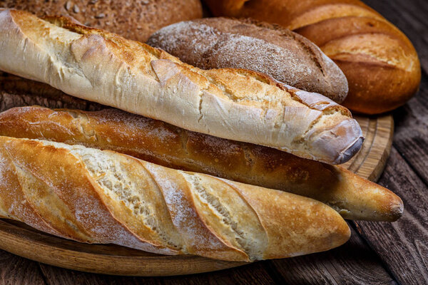 Assortment of baked bread on wooden table background