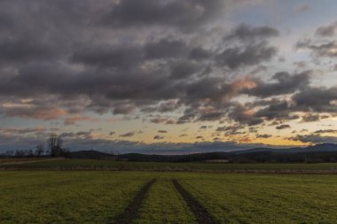 Path in color sunrise on green field near Vyhen village in south Bohemia