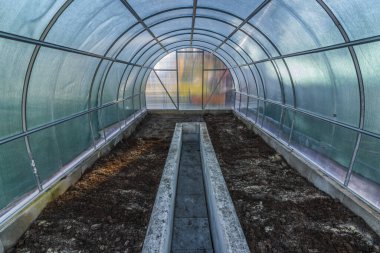 Bahar gelmeden önce beton duvarları ve plastik inşaatı olan boş renkli sera