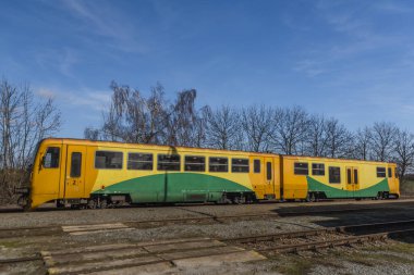 Kışın güneşli kış gününde Kojetice na Morave istasyonunda sarı renkli tren