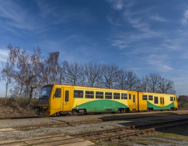 Kışın güneşli kış gününde Kojetice na Morave istasyonunda sarı renkli tren