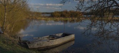 Lipno barajının sonu. Kuru baharda çimenler ve balıkçı teknesiyle güneşli bir gün.