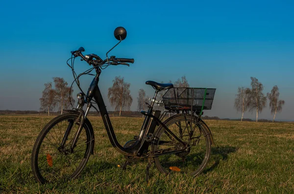 Budweis şehrinde yamaçta siyah elektrikli bisiklet Rüzgarlı ağaçlar ve ilkbahar çayırı