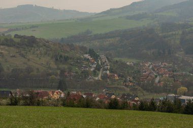 Moravya 'da bahar bulutlu bir günde Brumov kasabası ve çayır manzarası