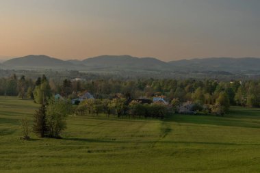 Kuzey Moravya 'daki Trojanovice köyü yakınlarında taze çayırlar ve yaşlı buidling' lerle renk batımı.