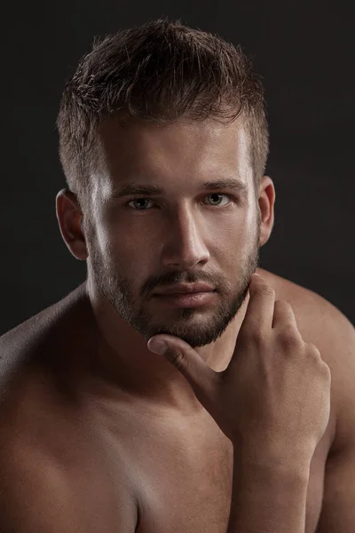 Homem modelo com um peito aberto em um fundo escuro, corpo muscular de um jovem em jeans. Tiro em um estúdio  . — Fotografia de Stock