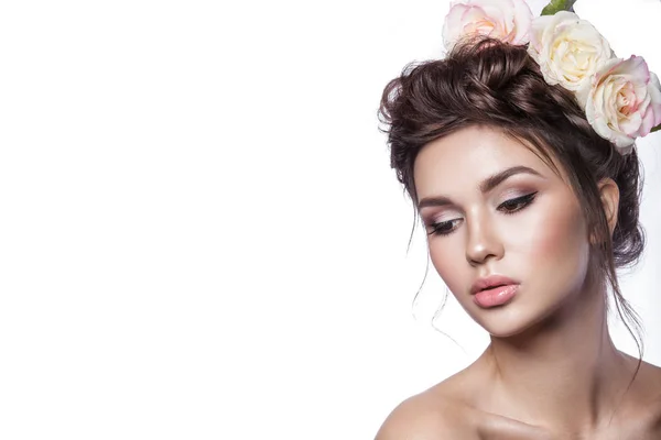 Belleza chica joven, piel limpia, hermoso maquillaje, trenzas de peinado y flores de rosas en el pelo . — Foto de Stock