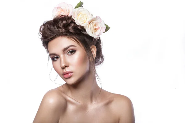 Belleza chica joven, piel limpia, hermoso maquillaje, trenzas de peinado y flores de rosas en el pelo . Imagen De Stock