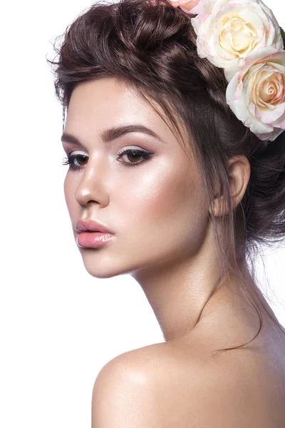Belleza chica joven, piel limpia, hermoso maquillaje, trenzas de peinado y flores de rosas en el pelo . Fotos De Stock
