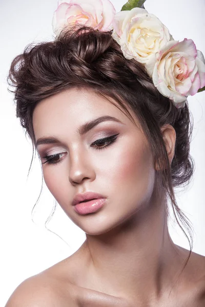 Belleza chica joven, piel limpia, hermoso maquillaje, trenzas de peinado y flores de rosas en el pelo . Fotos De Stock Sin Royalties Gratis