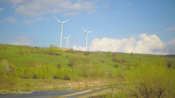 Ветровая электростанция на горе с небом и облаками и рекой, протекающей под ней — стоковое видео