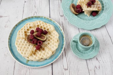 Ahududu ve incir, gözleme şeklinde yumuşak Belçika kalp bal turkuaz mavi plaka ve kahve ile kaplı. Rustik ahşap arka, üstten görünüm. Tatil sabah evde