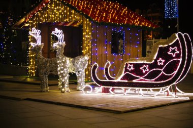 Noel dekorasyon - Ren geyiği ve atlı kızak. Noel ışıkları. Noel gecesi. Parlak kızak iki geyikler ile yaktı.