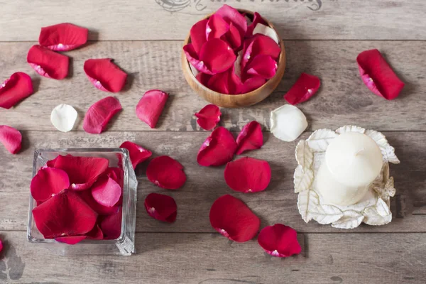 Jarrón de vidrio y arco de madera lleno de pétalos de rosa roja, vela de vainilla aromática blanca. Fondo de madera. Concepto de aromaterapia. Fondo romántico — Foto de Stock