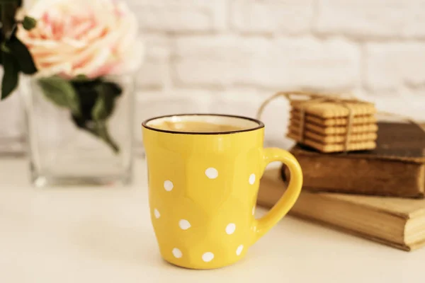 Kaffeetasse, Cappuccino, Latte, alte Bücher, Kekse und Rose auf weißem Tisch. graue Ziegelmauer. Freizeit Lifestylekonzept. leichter rustikaler Hintergrund — Stockfoto