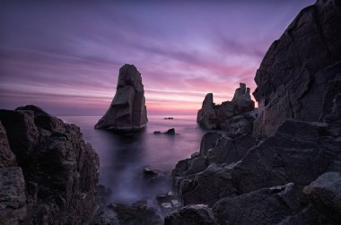 Şafak gizemleri. Sozopol, Bulgaristan yakınındaki Karadeniz sahilinde denize gündoğumu. Şafak gizemleri. Deniz ve kayalar, deniz manzarası. Kara bulutlar dramatik