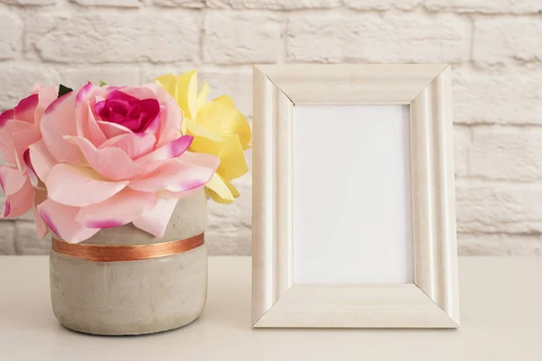 Rahmen-Attrappe. weiße Rahmen-Attrappe auf. cremefarbener Bilderrahmen, Vase mit rosa Rosen. Produktrahmen-Attrappe. Wandkunst-Displayvorlage, Ziegelwand — Stockfoto