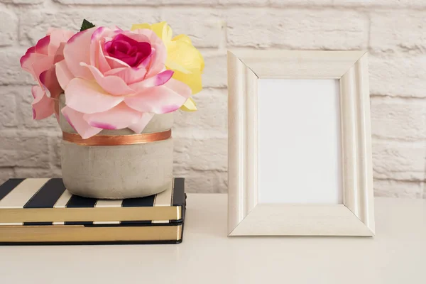 Rahmen-Attrappe. weiße Rahmen-Attrappe auf. Cremefarbener Bilderrahmen, Vase mit rosa Rosen auf Streifenheften. Produktrahmen-Attrappe. Wandkunst-Displayvorlage, Ziegelwand — Stockfoto