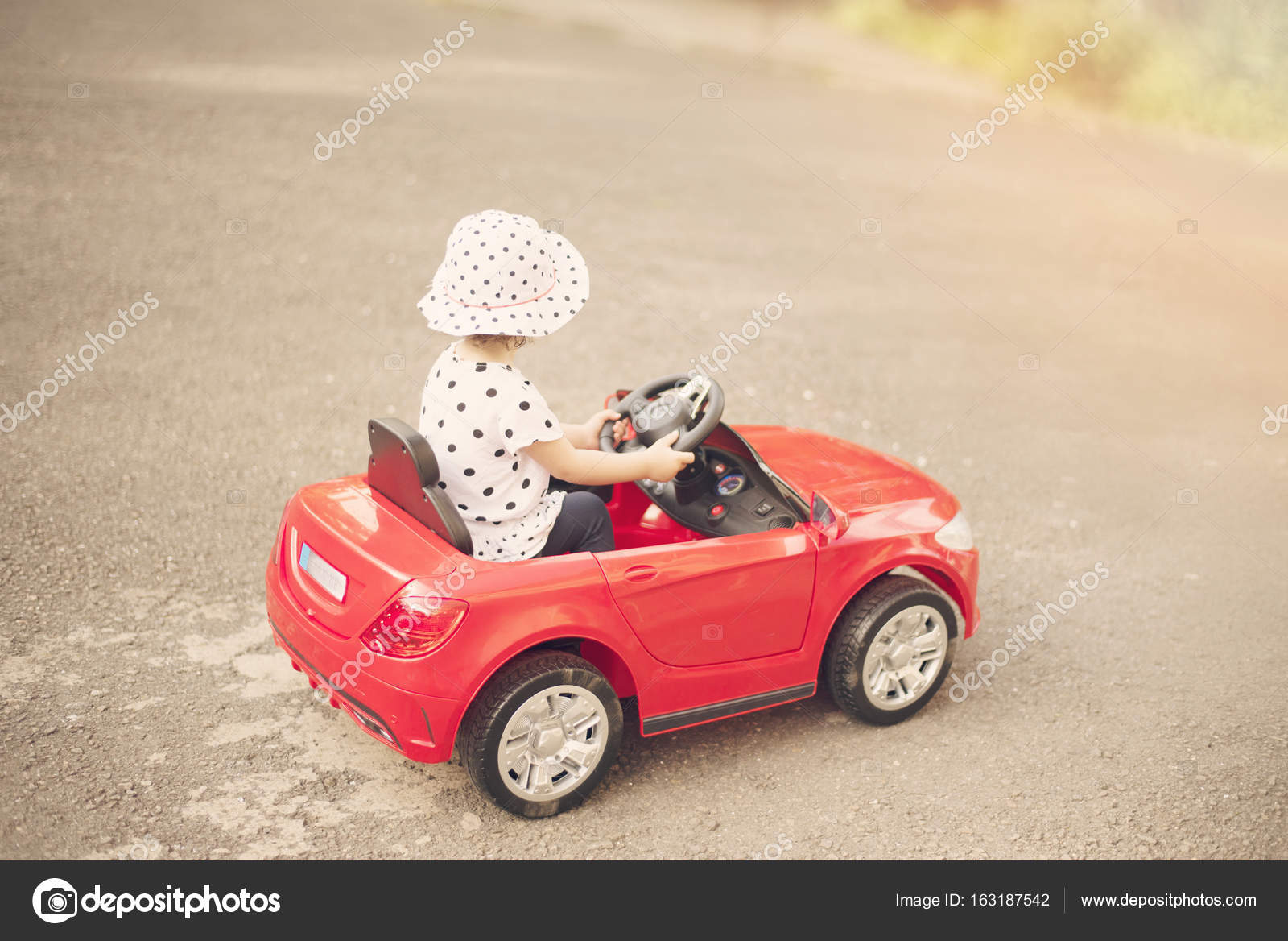 little girl driving toy car