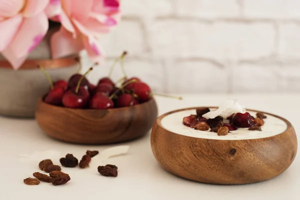 Flocos de aveia com iogurte e frutas. Cerejas, passas e batatas fritas. Café da manhã durante a noite. Conceito de alimentação saudável. Fitness Mood Diet. Lanche Luz de Verão. Brilhante parede de tijolo fundo . — Fotografia de Stock