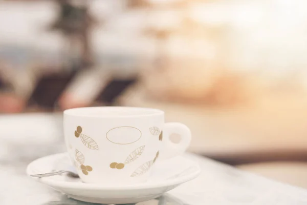 Una taza de café en una mesa, de cerca. En el fondo sombrillas borrosas en la playa. Sol, neblina, resplandor . — Foto de Stock