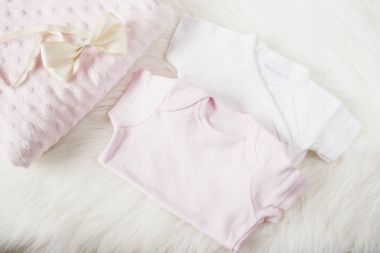 Bebek giysileri bir kız için. Bebek Tulum, tulumu, yay saç bandı ve pembe bebek bezi. Beyaz kürk halı üzerinde. Yeni doğan bebek kavramı. Bebek kız giysi seti