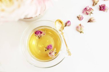 Bir fincan kurutulmuş güller ile sağlıklı bitki çayı. Mermer masa lambası, üstten görünüm üzerinde güzel taze çiçekler. Pembe buket kadın çalışma masası üzerinde. Blogger yaşam tarzı