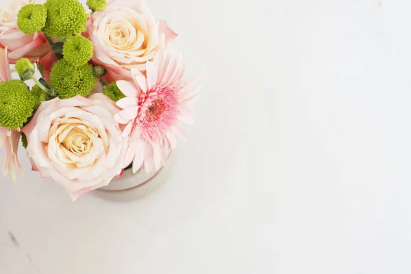 Hermosas flores frescas en la mesa de mármol claro, vista superior. Rosas rosadas y gerberas en un escritorio femenino. Estilo de vida blogger — Foto de Stock