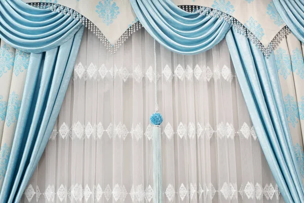 Μέρος της όμορφα ντυμένο κουρτινών για το παράθυρο στο δωμάτιο. Κοντινό πλάνο, των υφασματεμποριών κουρτινών με μενταγιόν. Πολυτελή κουρτίνα, εγχώριο ντεκόρ. Τουρκουάζ και μπλε πάνελ. Κουρτίνες δαντέλα — Φωτογραφία Αρχείου