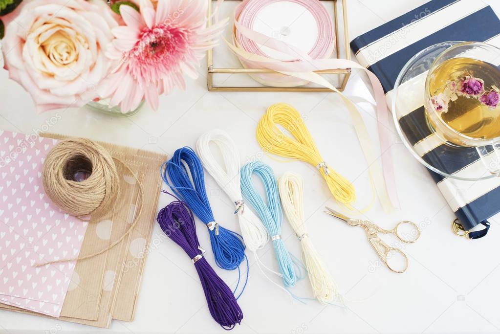 Handmade, craft concept. Materials for making string bracelets and handmade goods packaging - twine, ribbons. Feminine workplace concept. Freelance fashion femininity workspace in flat lay style with 